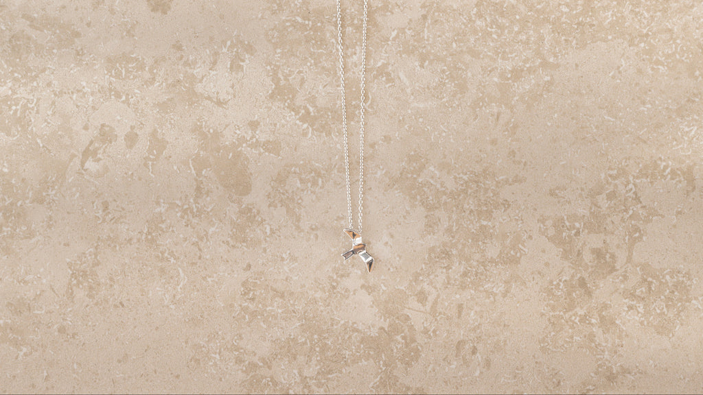 Bird necklace i 925 sterling silver från By K Design på beige bakgrund.
