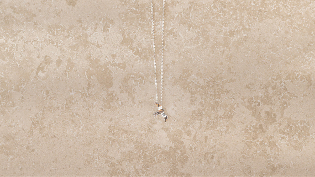 Bird necklace i 925 sterling silver från By K Design på beige bakgrund.